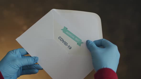 Person Opening Envelope with Certificate with Positive Results in Covid-19