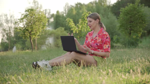A Middleaged Woman Sits on the Grass in the Park alt