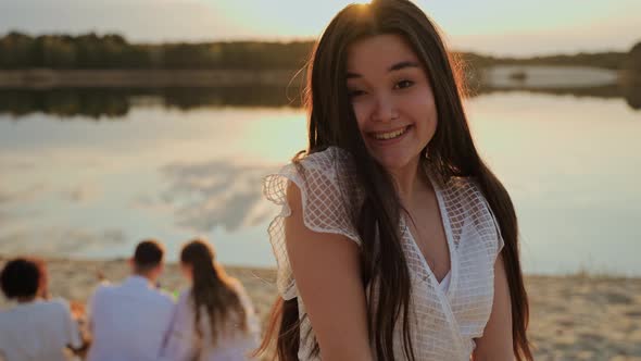 Beautiful Young Asian Girl Looks at Camera Having Fun on the Beach at Sunset