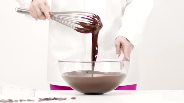 Chocolatier Takes Whisk Out of Melted Chocolate. Chocolate Streams Flow Slow Mo