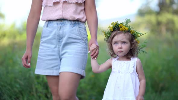 Happy Mother and Daughter with the Flower Wreath Walk in the Countryside