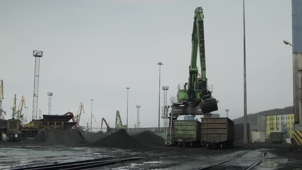 Group of Cranes Unloads Railway Cars with Coal at the Station During Rain