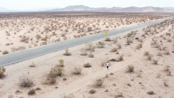 A man walking on a highway in the desert. alt