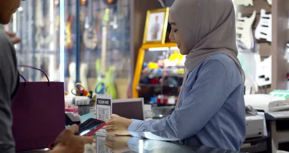 Young muslim man paying by scanning QR Code with smartphone
