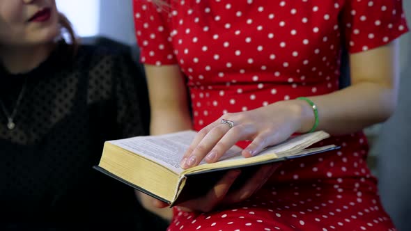 Young Wonen Are Reading a Book in the Living Room. alt