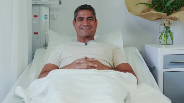 Front view of Caucasian male patient relaxing on hospital bed in hospital ward 4k alt
