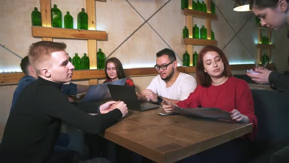 Waiter in Restaurant Takes Order From Group of Friends