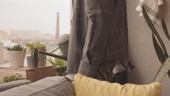 Man Watering Home Plants in Pots alt