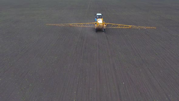 A Tractor Rides Across the Field Spraying the Crop, Shooting From the Air alt