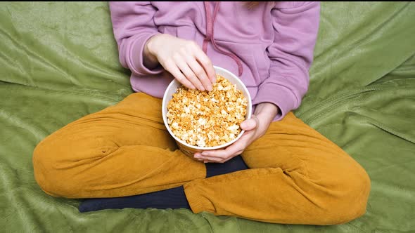 Clode Up View on Girl or Woman Holding a Popcorn While Watching a Movie in the Living Room