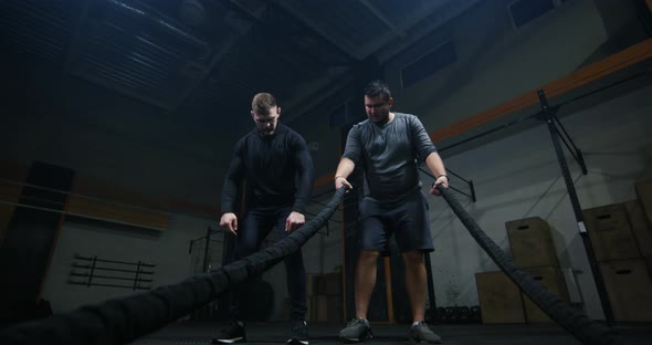 Trainer Overseeing Young Man Training with Battle Rope alt