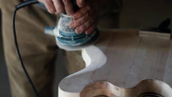 Craftsman forms a guitar in the shape of a wooden board