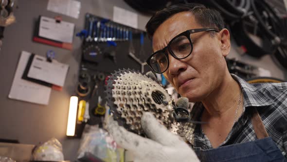 Asian senior man owner repairing and checking bicycle gears