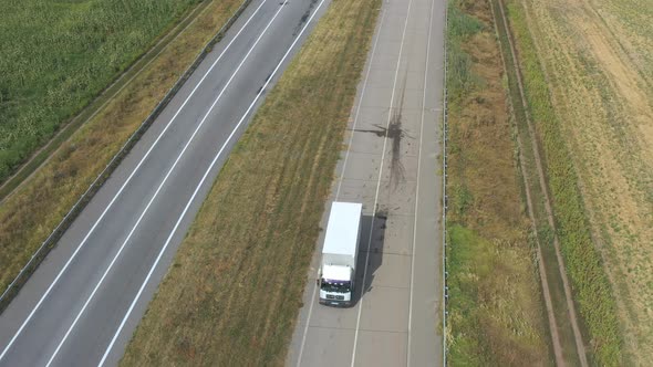 Aerial Shot of Truck with Cargo Trailer Driving on Empty Road and Transporting Goods. Flying Over