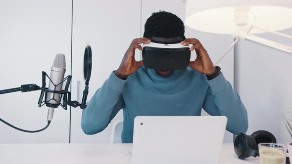 African American Man Checking a VR Glasses  Laptop and Microphone in Front of Him alt