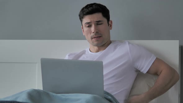 Young Man with Spinal Back Pain Sitting in Bed alt