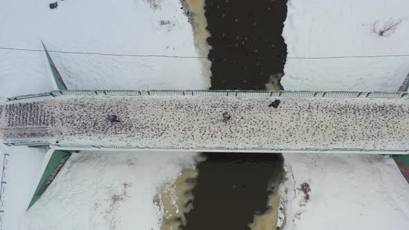 The City's Pedestrian Bridge People Walk Across the Bridge Over the River in Winter