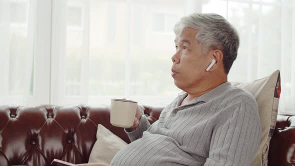 Senior man use wireless earphone listening music and drink coffee