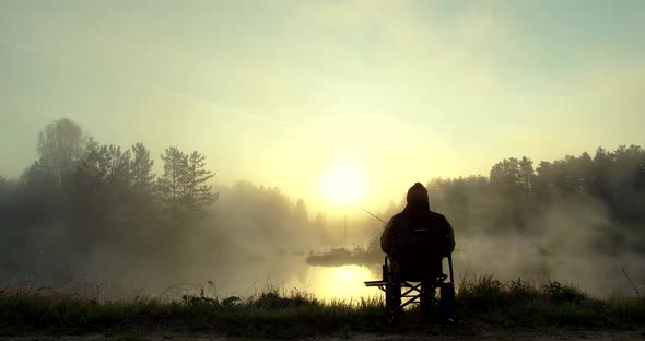 Unrecognizable Man Fishing in Lake at Dawn