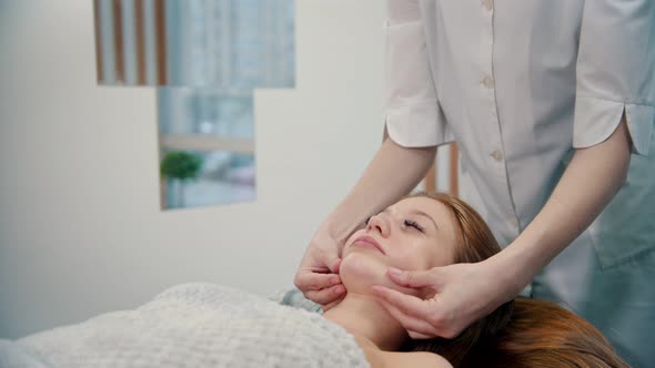 Massage - Massage Master Kneading Nasolabial Folds on the Face of a Young Woman alt
