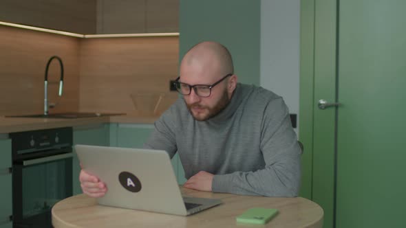 Young Adult Man Got Very Excited Reading a Good News on Laptop Working at Home alt