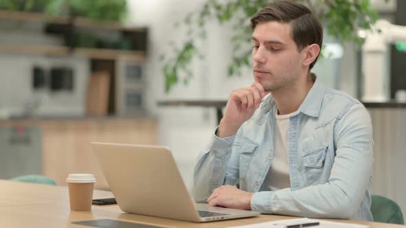 Creative Young Man with Laptop Thinking at Work alt