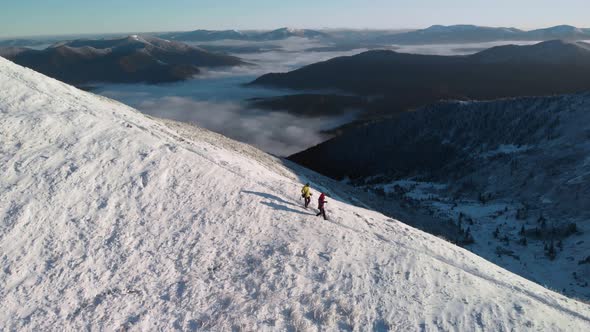 Two Mountaineers Descending a Mountain Ridge Covered in Snow