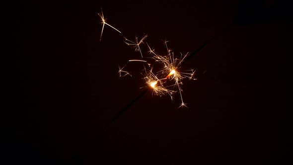A sparkler glows in the dark on Christmas night. Christmas parties, glowing sparklers.