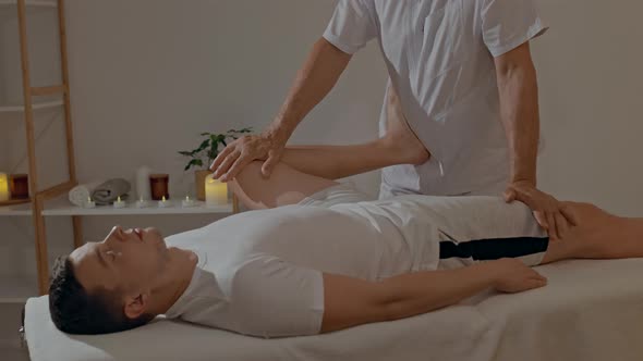 Strong and Concentrated Masseur Therapist in Uniform Making Manual Therapy for Sportsman