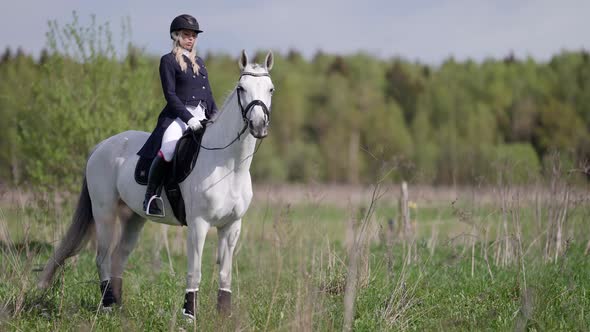 Professional Horse Riding Woman is Wearing Jockey Suit is Walking White Horse on Field alt