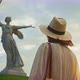 A young girl in a dress looking at Mother Motherland on the Mamayev Kurgan at sunset - VideoHive Item for Sale