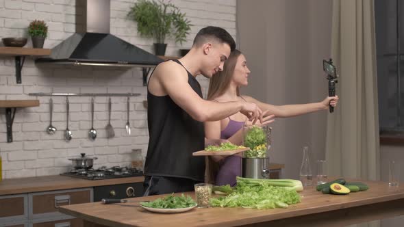 loving couple of athletes recording video food vlog about healthy cooking on phone camera alt