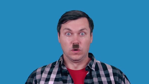 Funny portrait of a handsome man with a small mustache. Blue background.