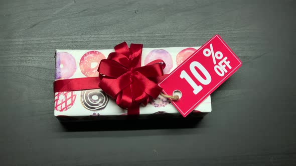 Gifts with discount. New Year holiday gift box on a black table. Top view. 10%