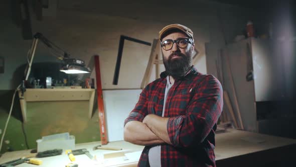 Portrait of a Bearded Man in Glasses Who is Standing with His Arms Crossed alt