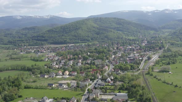 Flying above small city under Mountains 