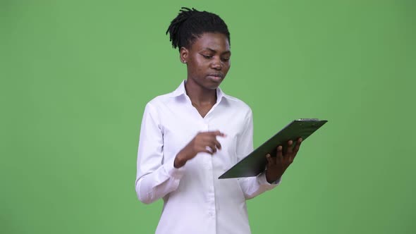 Young Beautiful African Businesswoman Thinking While Reading on Clipboard