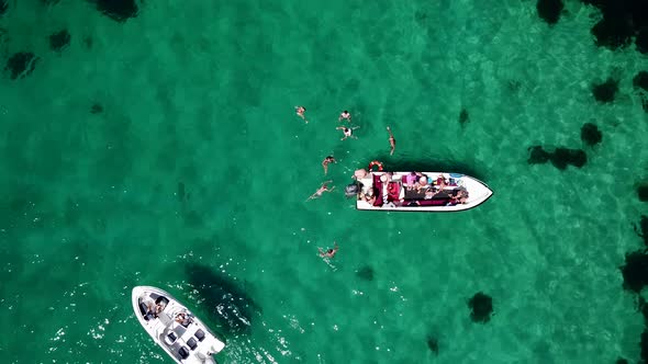 Bird's Eye View of Tourists Swimming in the Crystal Clear Sea Next to Tourist Boats alt
