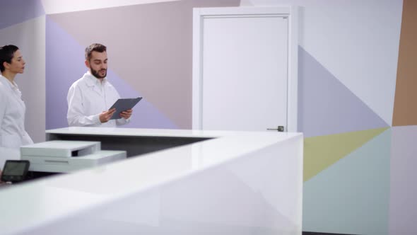Doctors in White Coats Walking along Hospital Hallway and Talking alt