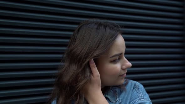 Portrait of a Young Woman with Ring Earrings Against a Dark Wall. the Camera Is Moving alt