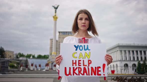 Woman in Embroidery Holds Poster Calling for Ukraine Support alt