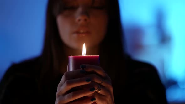 Young Pretty Witch Is Telling Fortune By Flame of Candle Closeup Portrait in Darkness alt