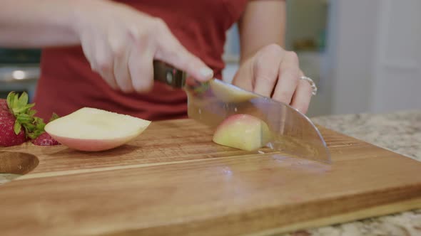 Woman cutting up a fresh apple on cutting board alt