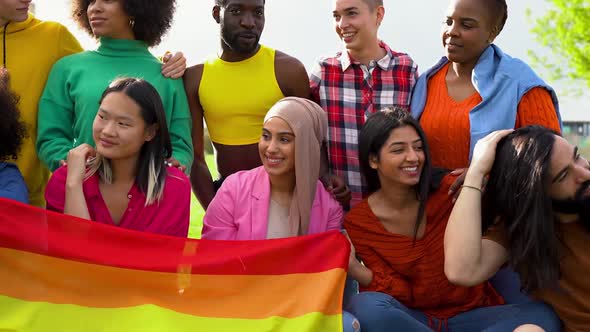Group of multiracial people having fun at city park with rainbow flag - LGBT gay pride event