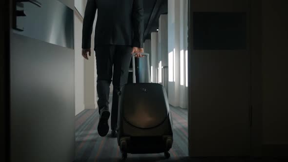 Businessman with Travel Suitcase Walking at Hotel Corridor. Man Arriving Hotel alt