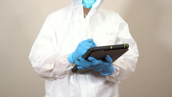 female doctor dressed in ppe suit using tablet to consult information during the service alt