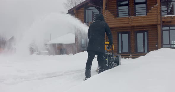 Man Removes Snow with Snowblower in Yard at Snowfall in Slow Motion alt