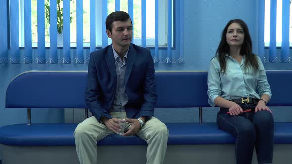 Man an Woman Sits on a Chair and Waits for the Turn alt