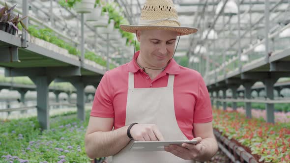 Camera Approaches To Confident Caucasian Man Typing on Tablet and Smiling. Front View Portrait of alt