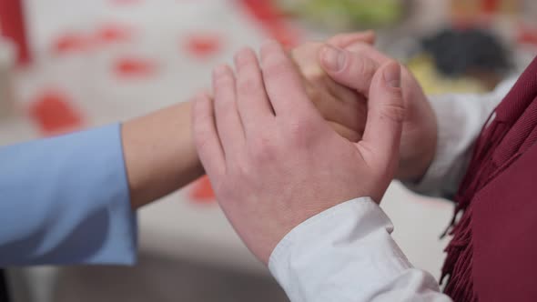 Closeup of Unrecognizable Man and Woman Holding Hands at Valentine's Dinner Table alt
